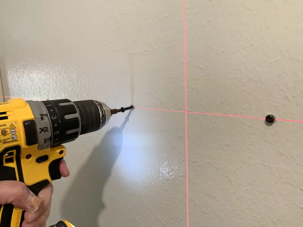 using drill to screw into anchors on laser level guidelines