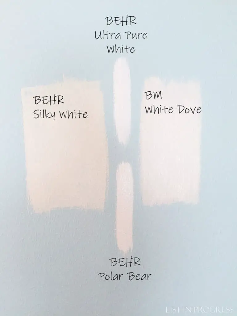 paint swatches on walls: behr silky white, behr polar bear, behr ultra pure white, and ben moore white dove